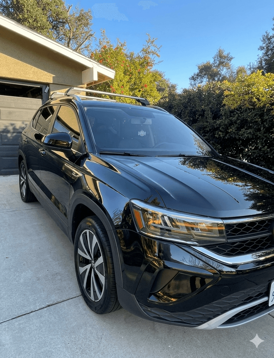 Glossy black Volkswagen SUV on a sunny concrete driveway with sharp reflections on the hood and fenders